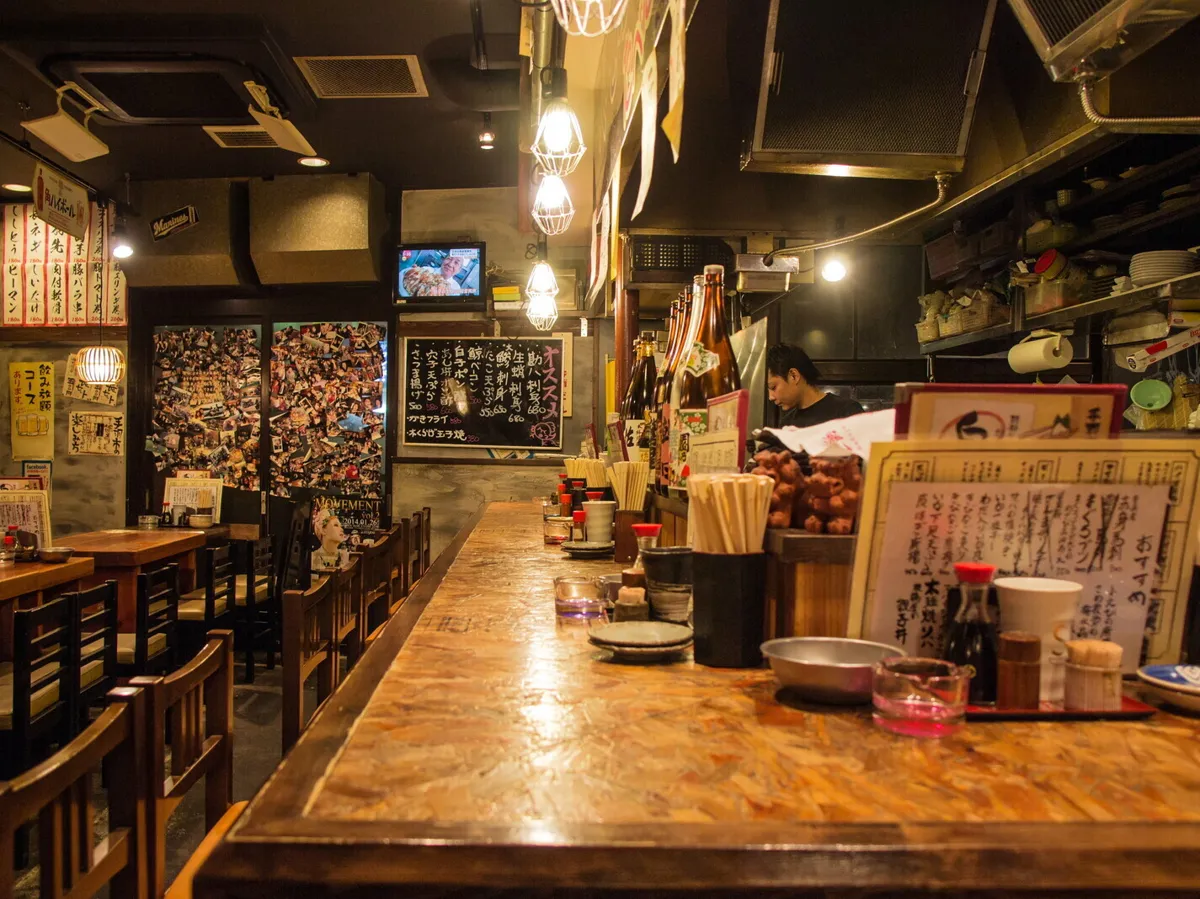厨房に面したカウンター席。黒板のおすすめメニューと日本酒の瓶が並ぶ
